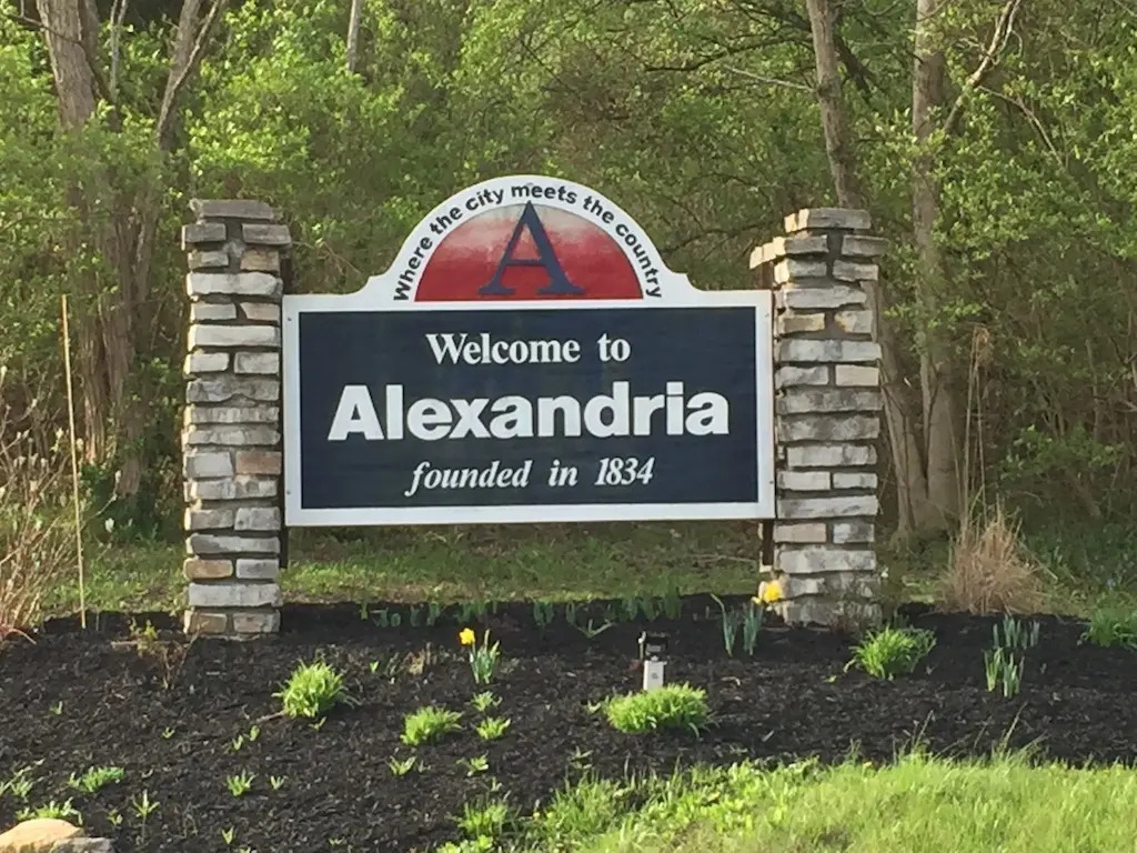 Alexandria KY | Helmer Somers Law Welcome to Alexandria city sign with 'founded in 1834' and stone pillars, set among shrubs and trees.
