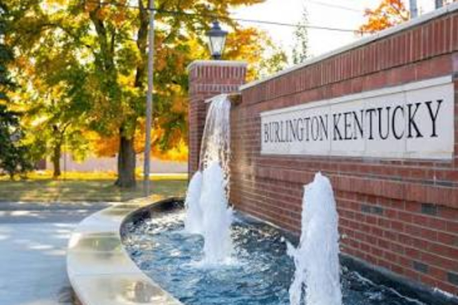 Burlington Ky 1 | Helmer Somers Law Brick town sign reading Burlington Kentucky beside a water fountain feature with falling water and autumn trees in the background