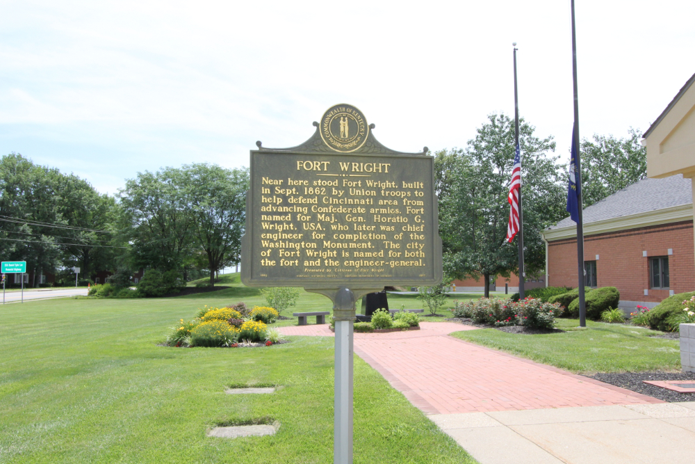 Fort-Wright 1 | Helmer Somers Law Bronze historical marker titled Fort Wright on a post, noting its 1862 construction by Union troops to defend Cincinnati, with a brick building, flagpoles, and landscaped lawn in the background.